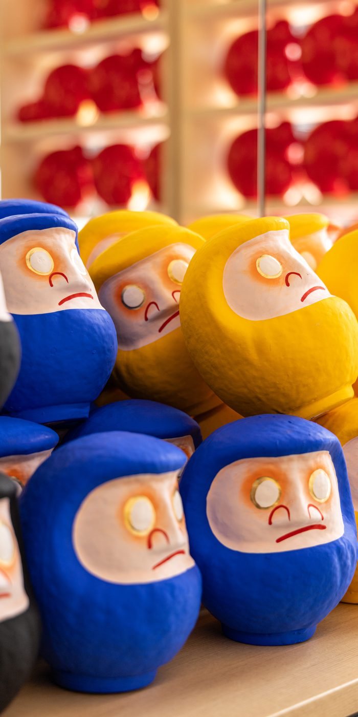 Blue, yellow and black Daruma dolls stacked on the shelf at DARUMA LAB. in Shinsaibashi